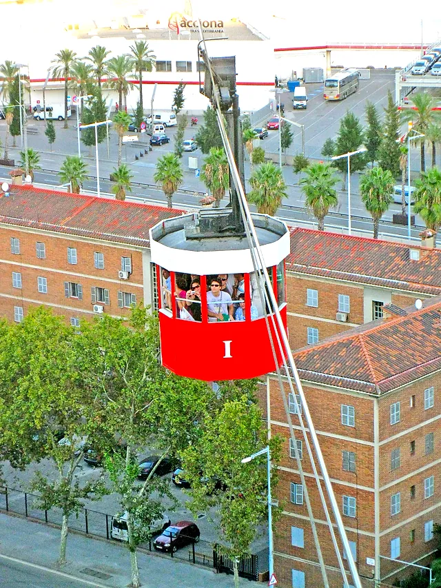 A red cabin of the Port Cable Car suspended above the harbour buildings